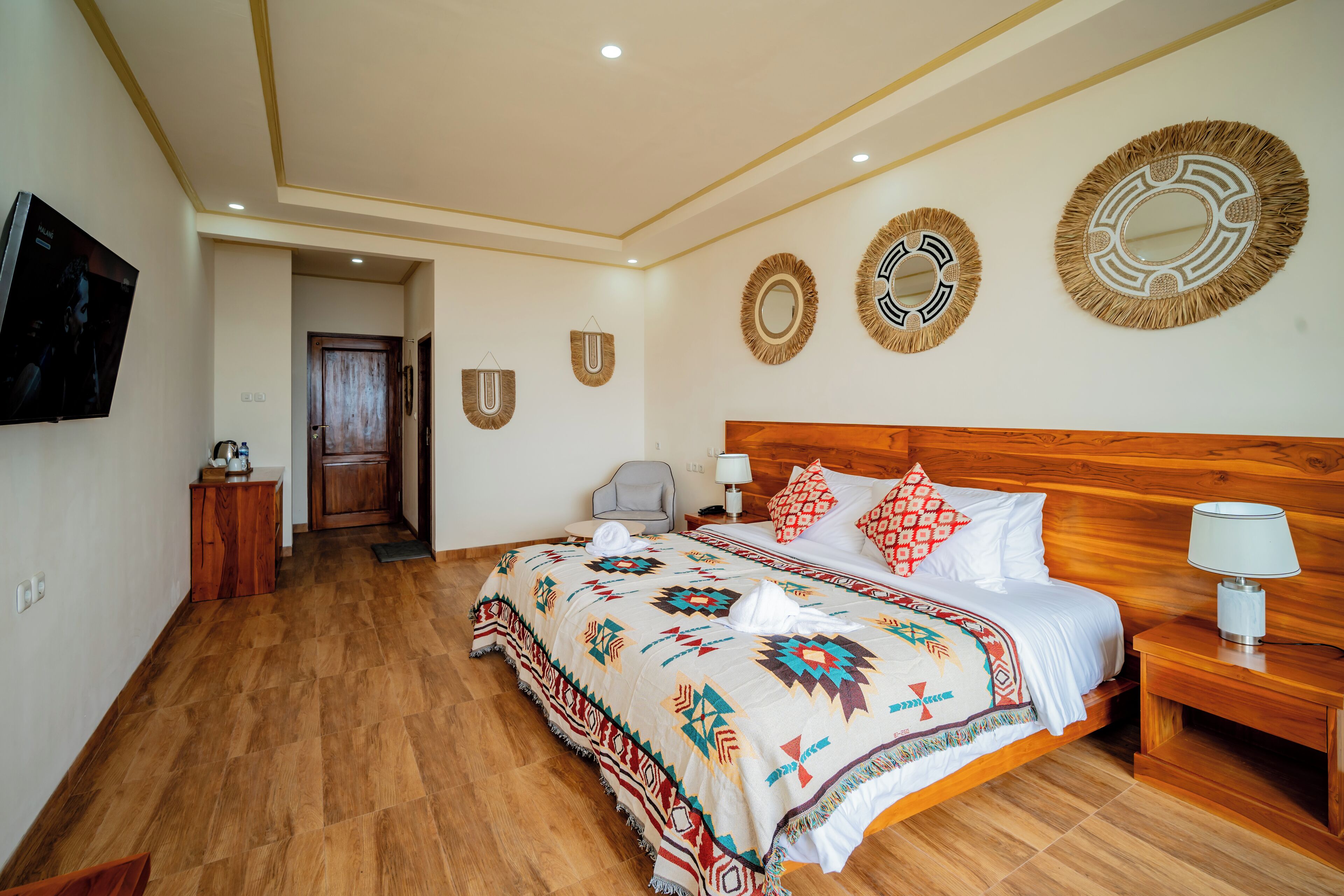 A hotel room with a wooden bed, a nightstand, a TV, and decorative wall mirrors.