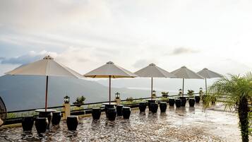 A terrace with outdoor seating, umbrellas, and potted plants.