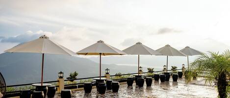 Une terrasse avec des sièges extérieurs, des parasols et des plantes en pot.