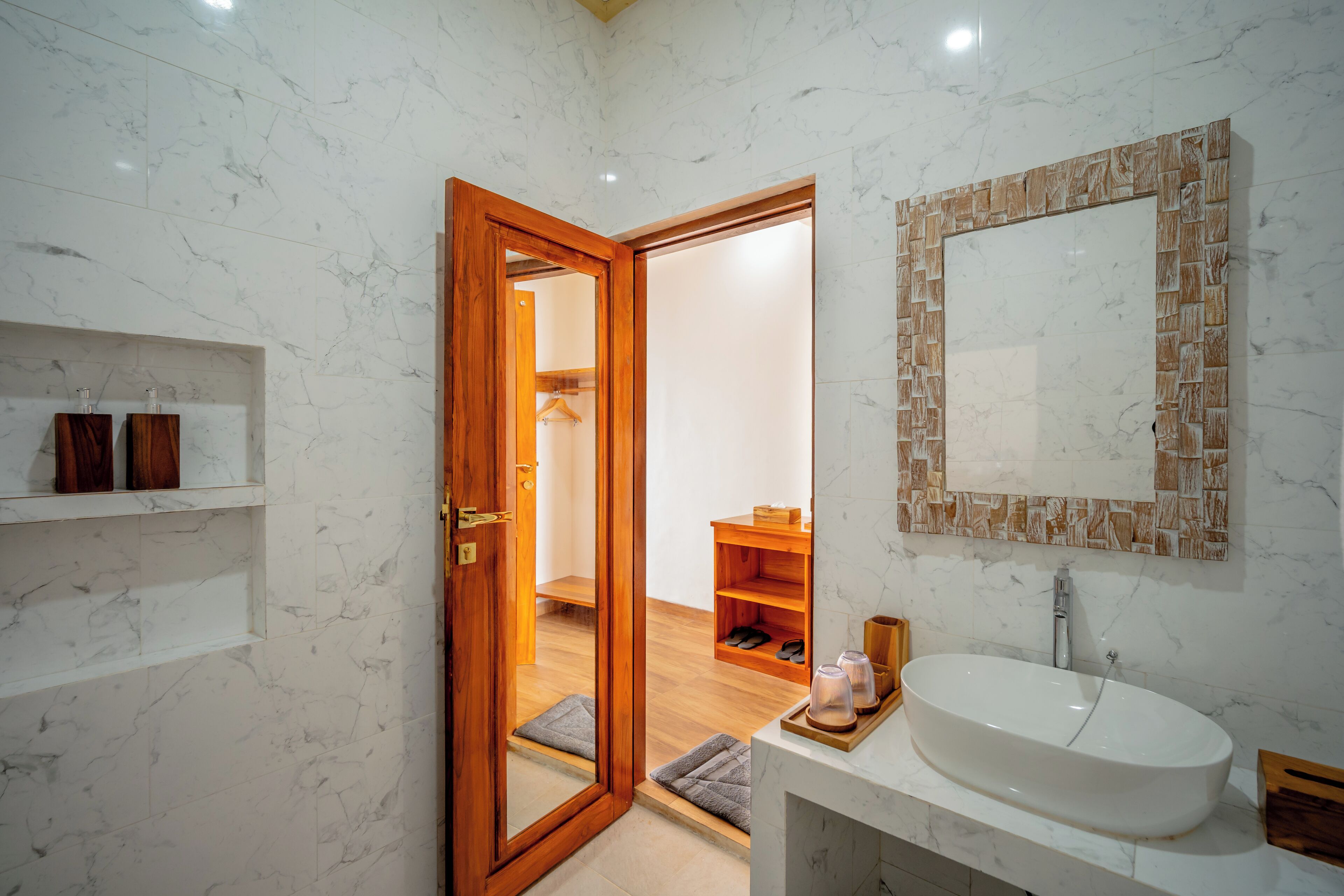 A bathroom with a wooden door, a white sink, and a mirror with a wooden frame.