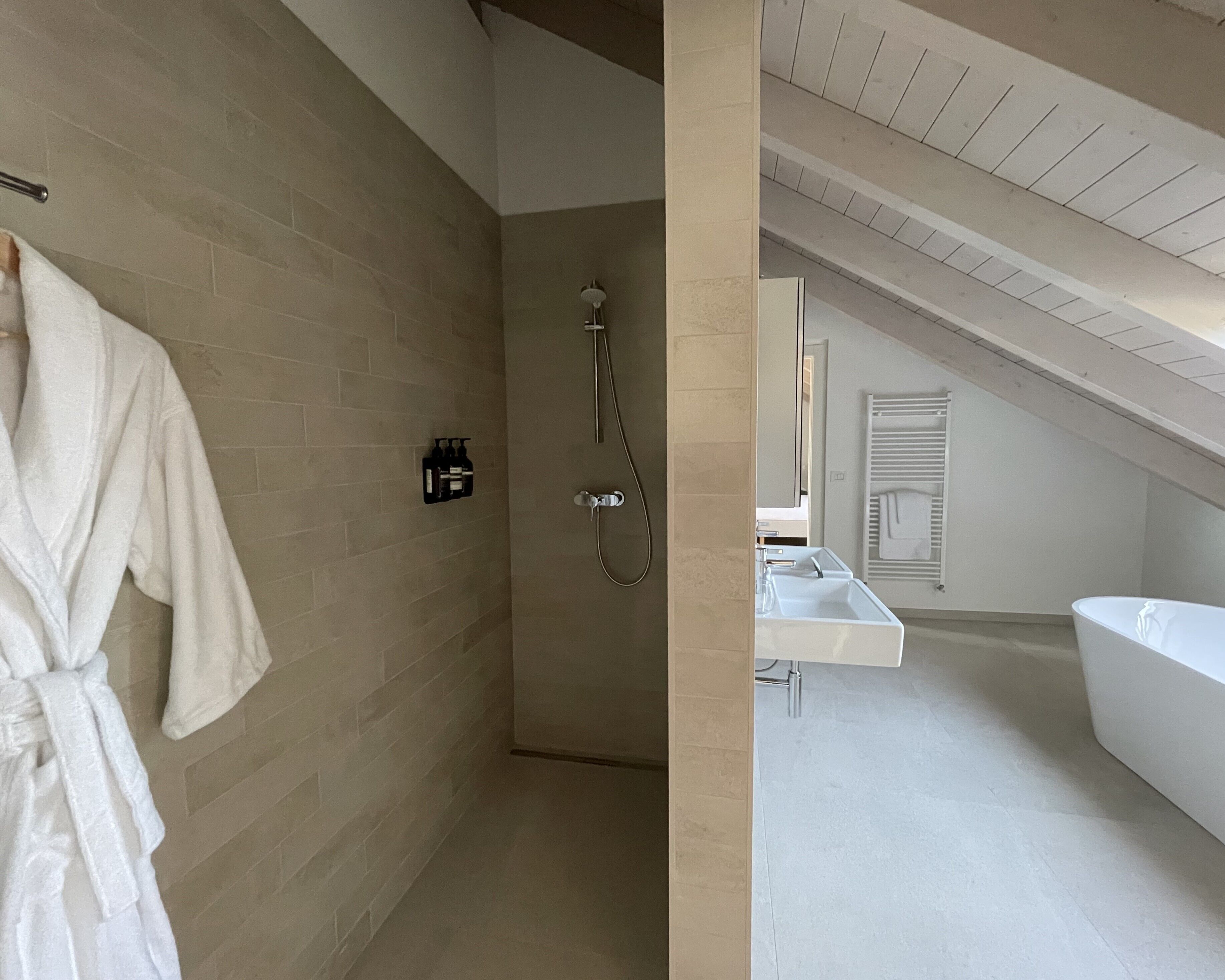 Un baño moderno con ducha a ras de suelo, una bañera grande y un lavamanos blanco.