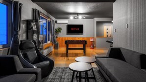 Un salon moderne avec un baby-foot, un canapé et un téléviseur à écran plat affichant le logo « NETFLIX ».