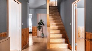 Un couloir avec un plancher en bois, un escalier et une plante en pot.