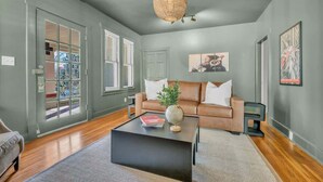 A modern living room with a brown leather sofa, a black coffee table, and a large window with blinds.