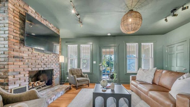 A living room with a brick fireplace, a leather sofa, and a large window.