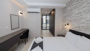 A modern hotel room with a bed, desk, and chair. There is a large window providing a view of the city. - A bright and cozy Mellieha apartment with modern comforts, close to the beach, shops, and transport—perfect for a relaxing family or couple’s getaway. (Il-Mellieħa)