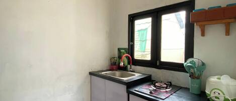 A small kitchen with a sink, a window, and a trash bin.