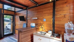 Ein Holzinnenraum mit Küchenzeile, inklusive Spüle, Wasserkocher und Wasserspender.