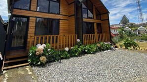 Ein zweistöckiges Holzhaus mit großen Fenstern und einer Schotterzufahrt.