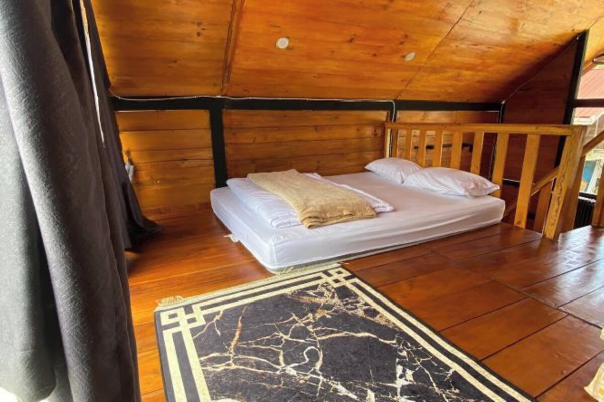 A wooden cabin room with a bed, a wooden ceiling, and a floor.