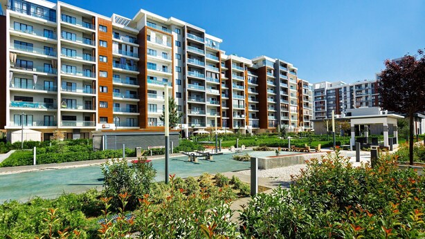 Un immeuble d’appartements moderne doté de nombreux balcons, d’une cour aménagée et d’un petit pavillon.
