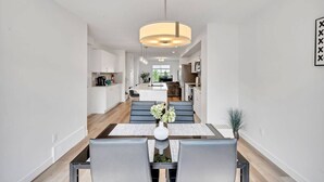 A modern kitchen with white cabinets, a central island, and a hanging pendant light. - Beautiful 3 bedroom home in Glenridding ravine  (Edmonton)