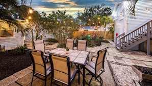A patio with a table and chairs, surrounded by plants and a wooden deck. - 1 Mi to Lake Worth Beach Park: Chic Studio (Lake Worth Beach)