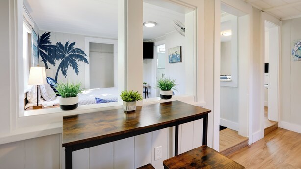 A hallway with a wooden bench, a small table with potted plants, and a large mirror reflecting the room. - 1 Mi to Lake Worth Beach Park: Chic Studio (Lake Worth Beach)