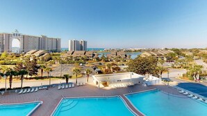 A resort with multiple swimming pools, a large building with an arched entrance, and a view of the sea. - Gulf Views | Resort | Pools | Gulf View Getaway | Pickleball | Miramar Beach (Destin)