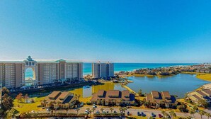 A resort with beachfront villas, a central building with a distinctive arch, and a marina. - Gulf Views | Resort | Pools | Gulf View Getaway | Pickleball | Miramar Beach (Destin)