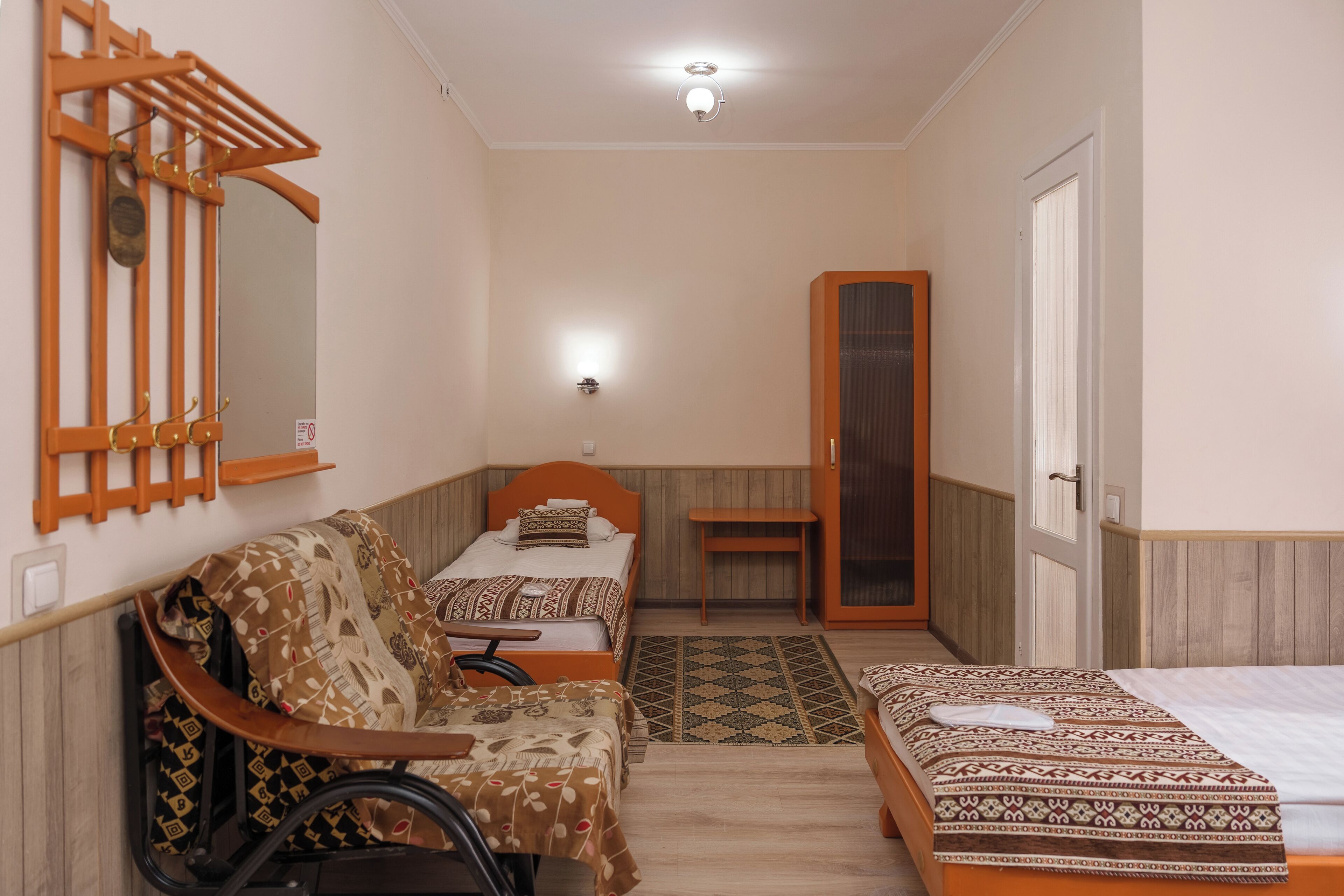 Une chambre avec deux lits, un fauteuil roulant, un miroir et une armoire en bois.
