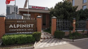 A hotel named 'Alpinist Conference Hall' with a wooden sign, brick exterior, and a gated entrance.