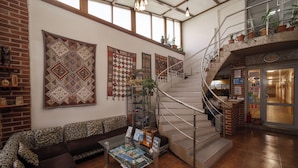 A spacious lobby with a staircase, patterned wall decorations, a seating area, and a coffee table with magazines.