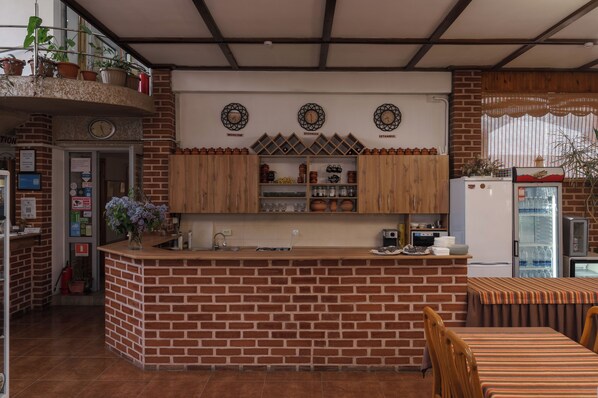 A kitchen with brick walls, wooden cabinets, and a central island. There are clocks on the wall and a refrigerator with a freezer.