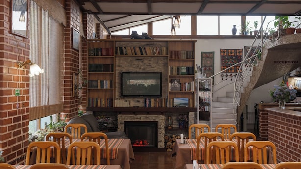 A cozy restaurant with brick walls, a fireplace, and a staircase leading to a reception area.