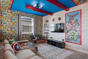 A living room with a colorful comic book wall, a large superhero painting, and a cozy seating area. - Chic 5Bed Home close to Disney parks (Kissimmee)