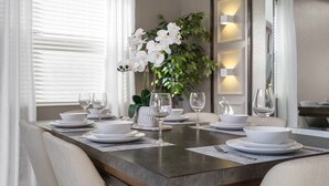 A dining table set with white plates, bowls, and wine glasses, surrounded by chairs. - Chic 5Bed Home close to Disney parks (Kissimmee)