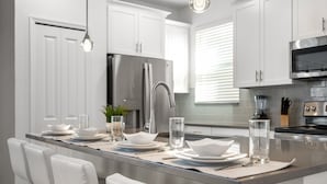 A modern kitchen with white cabinetry, stainless steel appliances, and a central island with seating.