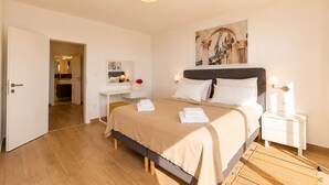 A bedroom with a bed, bedside tables, a desk, a mirror, and a painting on the wall.