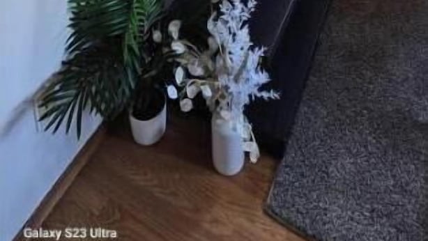Una sala de estar con un televisor de pantalla plana grande montado en la pared, un reloj y una pequeña mesa con adornos.