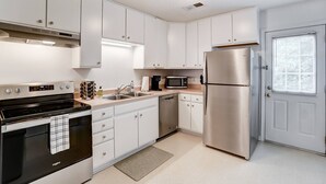 A modern kitchen with white cabinets, stainless steel appliances, and a built-in oven. - Cozy Bungalow in Wingate w Patio, Grill, Firepit - Easy Access To Bypass & Monroe! +15% Off Stay! (Wingate)