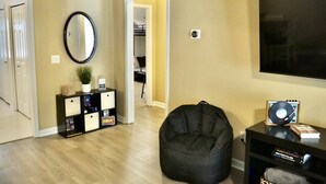 A living room with a black bean bag, a black TV stand with a record player, and a mirror on the wall. - Cozy Bungalow in Wingate w Patio, Grill, Firepit - Easy Access To Bypass & Monroe! +15% Off Stay! (Wingate)