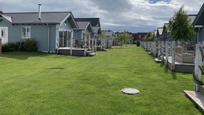 A row of blue mobile homes with attached porches and a grassy yard.