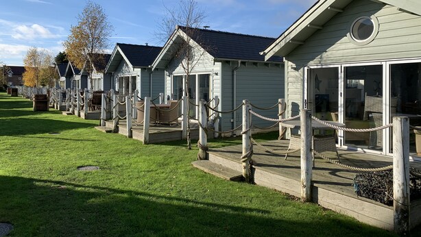 A row of light-colored, single-story cabins with large windows and a covered porch area.