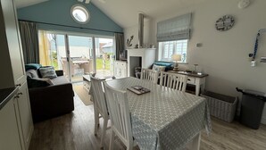 A compact living space with a dining area, kitchenette, and a view through a sliding glass door to an outdoor patio.