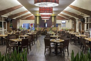 Un restaurante espacioso con techos altos, piso de madera y numerosas mesas y sillas.