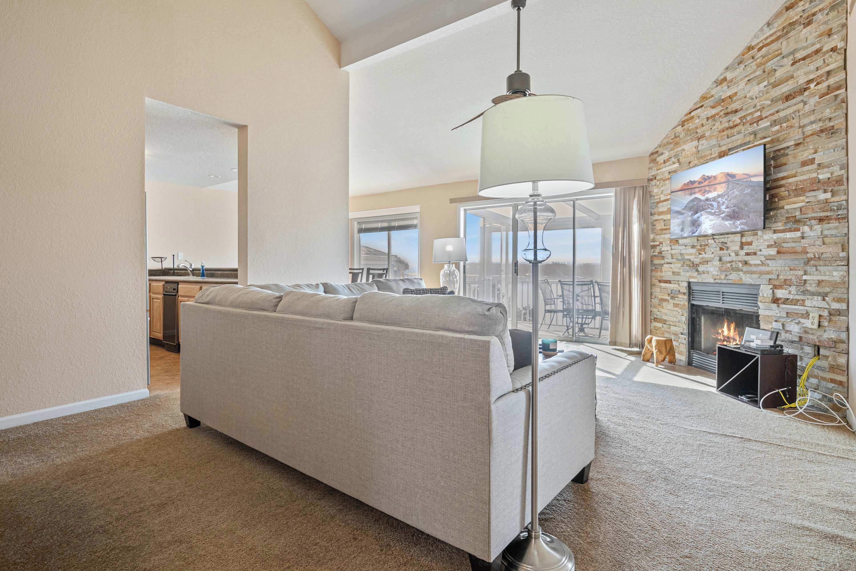 A modern living room with a sofa, a floor lamp, a fireplace, and a stone wall.