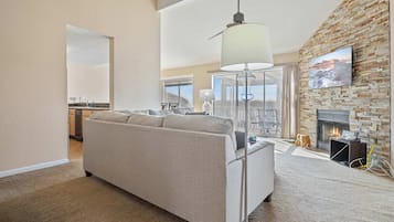 A modern living room with a sofa, a floor lamp, a fireplace, and a stone wall.