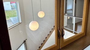 A staircase with wooden railings and a glass door leading to a room with a bed and a window. - ADVENTURe (Furano)