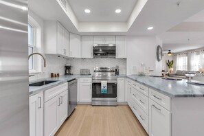 Una cocina moderna con armarios blancos, electrodomésticos de acero inoxidable y suelo de madera.