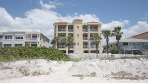 A beachfront hotel with multiple floors, balconies, and a sandy beach in the foreground. - Updated! Beachside Bi-level Unit, Sleeps 10! FREE Activities! Pool, FREE Parking ~ C400 Sun & Sea (Indian Rocks Beach)