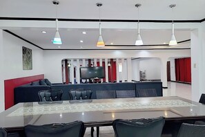 A modern dining area with a glass table, black chairs, and a red accent wall. - Jewelry Resort and Villas Tagaytay (Silang)
