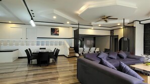 A modern living room with a sofa, a dining area with a table and chairs, and a staircase leading to an upper floor. - Jewelry Resort and Villas Tagaytay (Silang)
