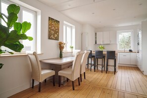 Een moderne keuken met witte kastjes, een houten aanrecht en een eethoek met een houten tafel en stoelen.