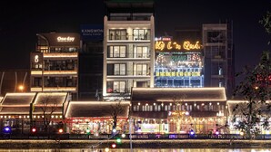 Un hôtel avec une enseigne au néon indiquant « Green Bay Hotel », et des bâtiments adjacents dotés d’enseignes lumineuses.
