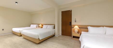 Habitación de hotel con tres camas, cabeceros de madera y lámparas de noche.