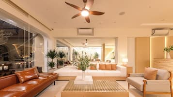 A modern hotel lobby with leather sofas, a wooden coffee table, and a large plant centerpiece.