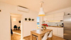 Una cocina moderna con armarios blancos, una mesa de comedor de madera y un refrigerador de acero inoxidable.