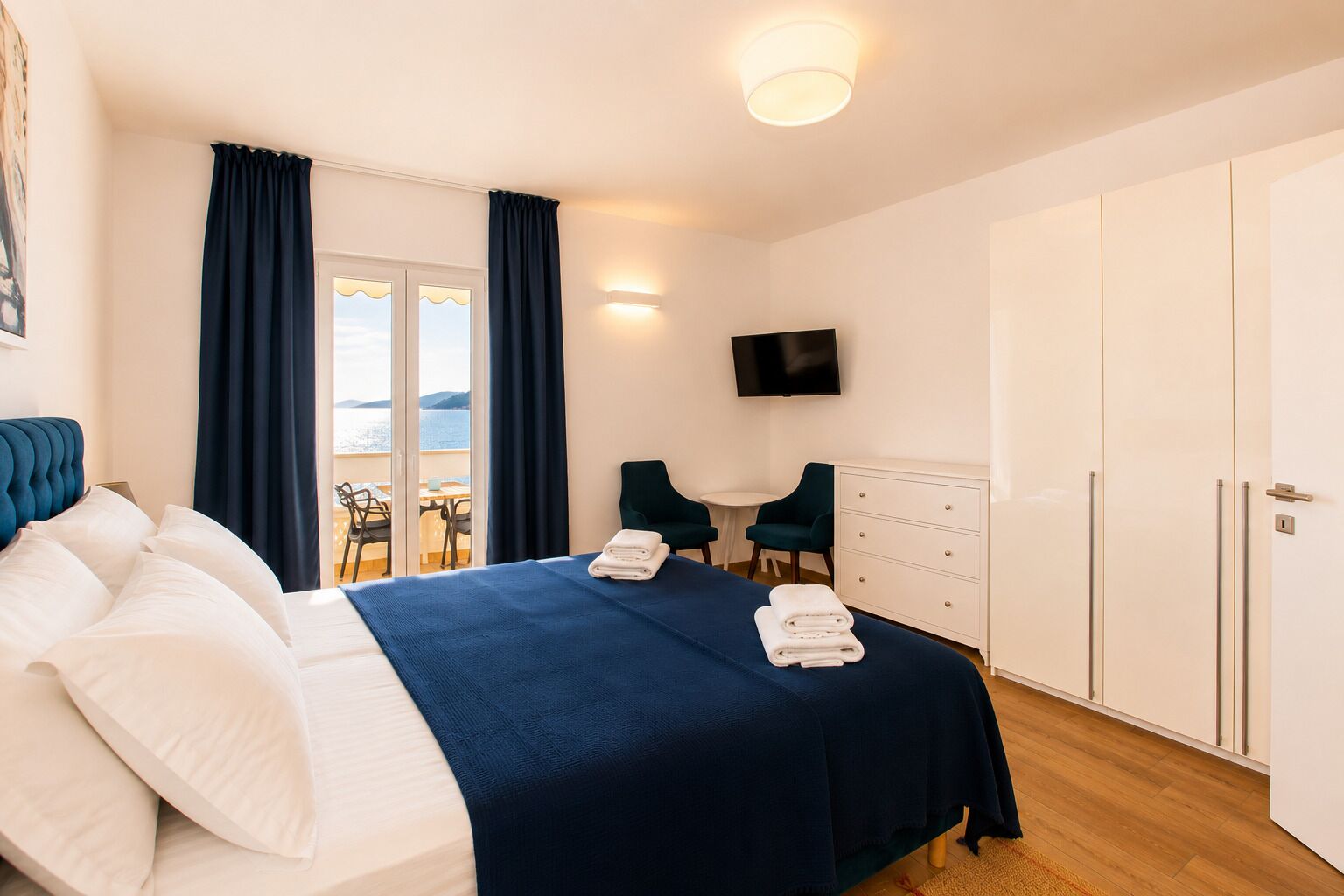 A hotel room with a bed, a desk, two chairs, a TV, and a wardrobe.