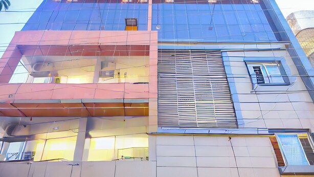 A multi-story building with a modern architectural design, featuring large windows and a mix of glass and metal elements. - Hotel Happy Stay  (Bhopal)